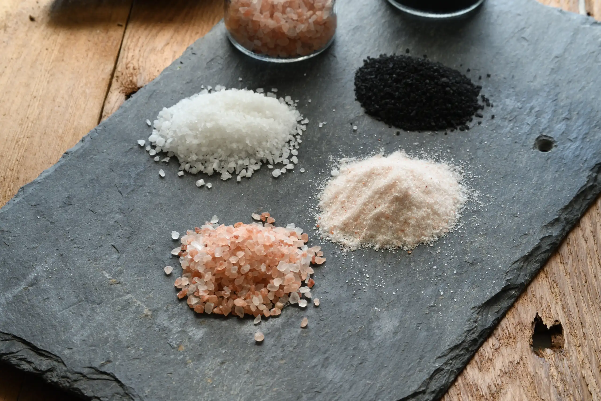 Photo showcasing different colors of Himalayan salt grains - pink, white, red, and black - highlighting their unique characteristics and culinary uses.